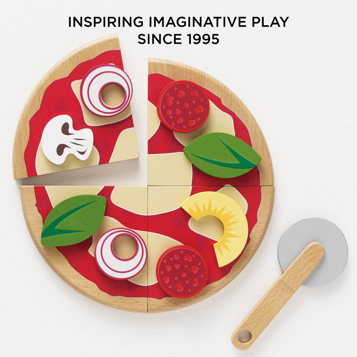 A wooden pizza topped with basil and salami sits ready for slicing in Le Toy Van's Pizza Set