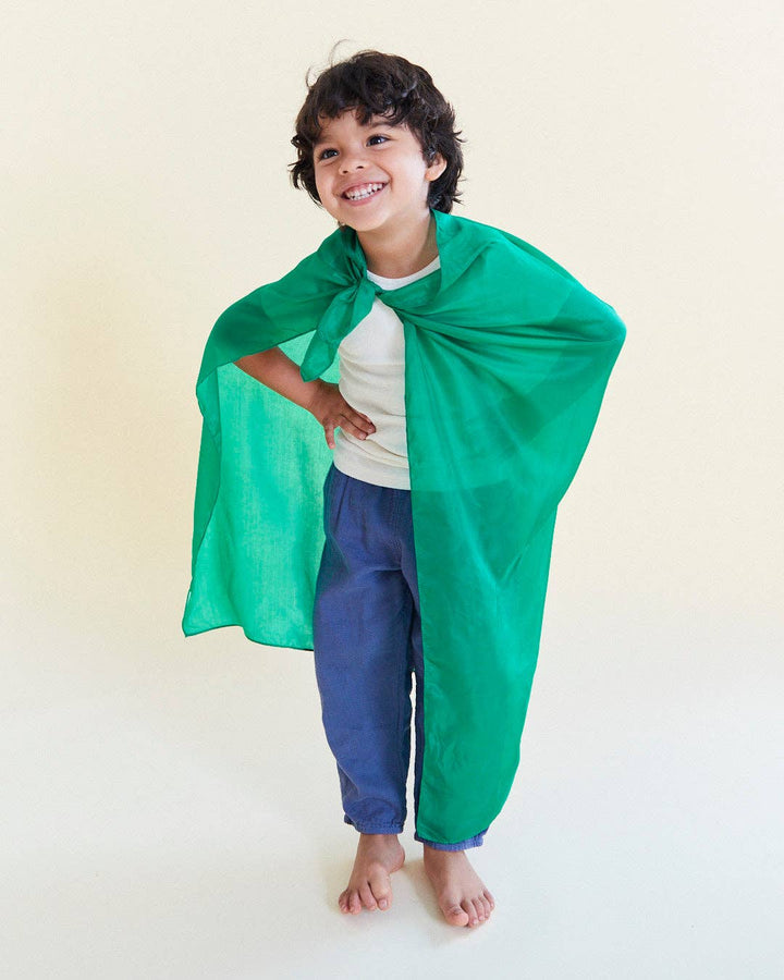 Child wearing a green Sarah's Silks Solid Color Playsilk as a dress up cape, a favorite dress up toy