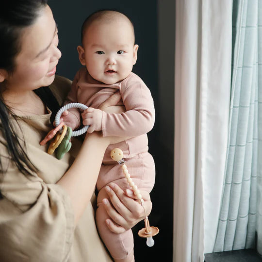 woman holding baby wearing blush pink shirt and soft pants designed for infant comfort