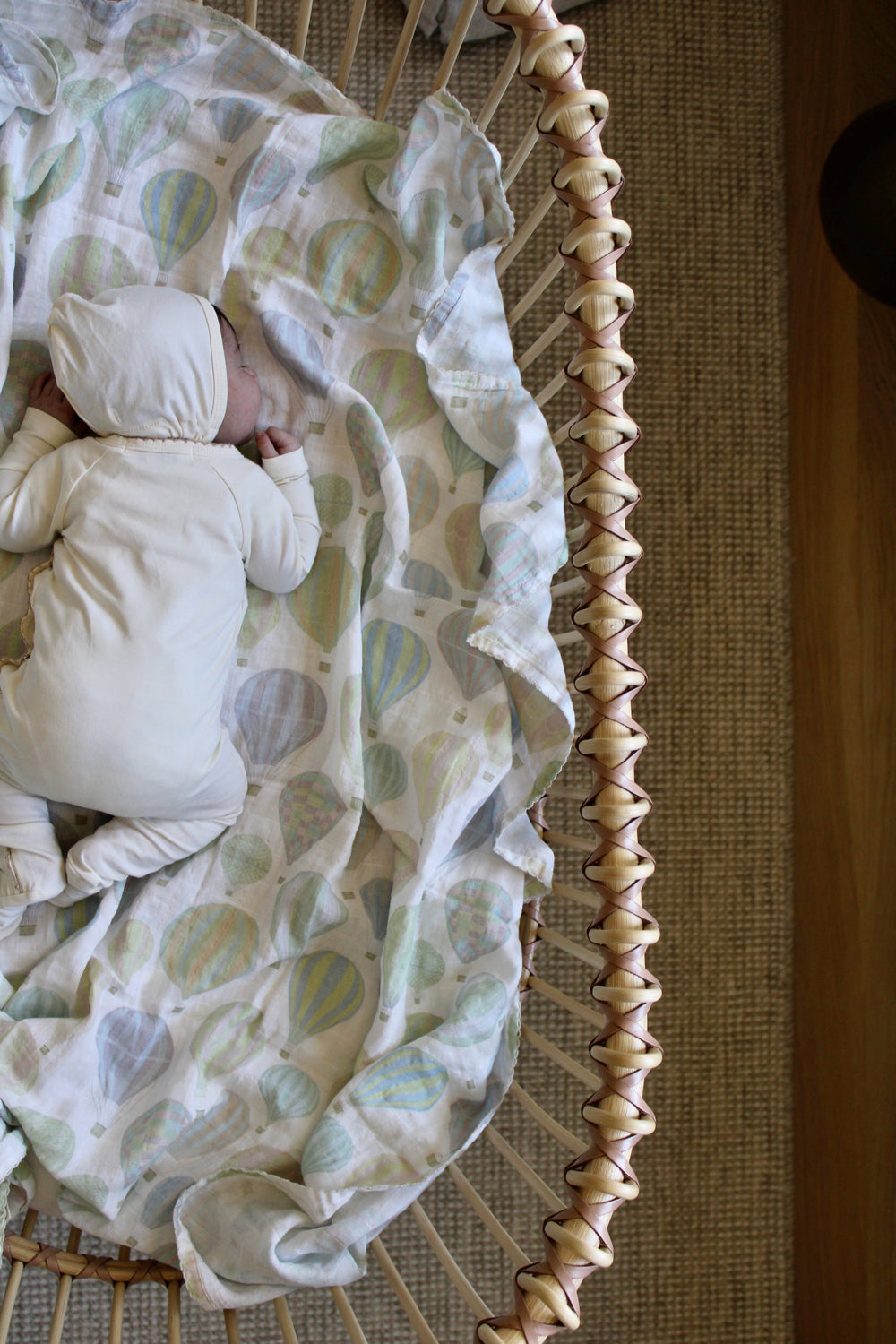 Little Threads air balloon muslin blanket in bassinet, soft organic cotton swaddle for newborn sleep and nursery bedding style