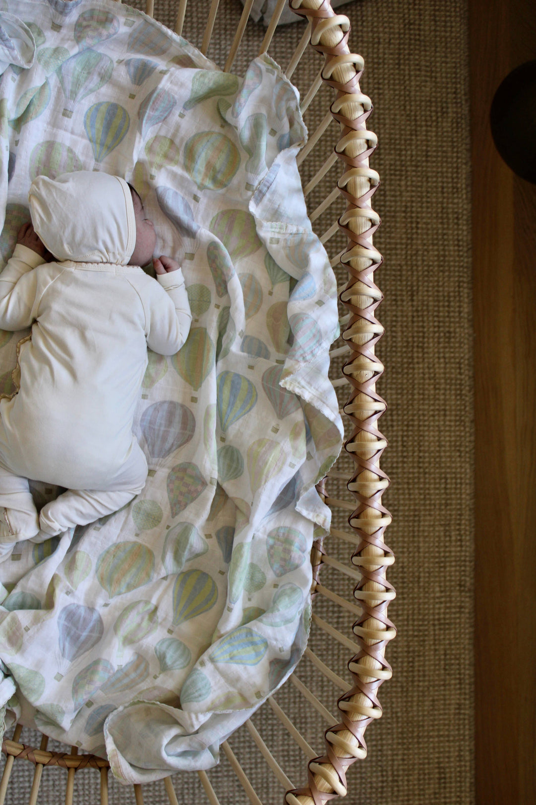 Little Threads air balloon muslin blanket in bassinet, soft organic cotton swaddle for newborn sleep and nursery bedding style