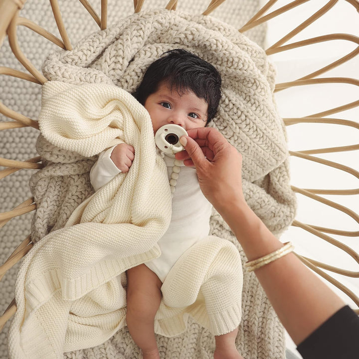 Baby snuggling the soft and durable Heritage Knitted Blanket for newborns, designed by Bleu La La in Butter Cream