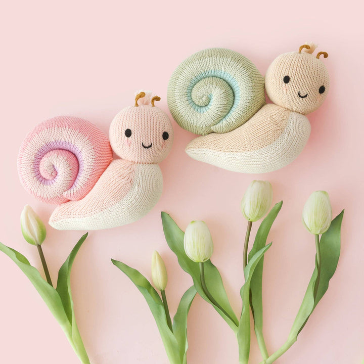 Cuddle + Kind Baby Snail Peony — hand-knit pink stuffed animal snail displayed in nursery setting
