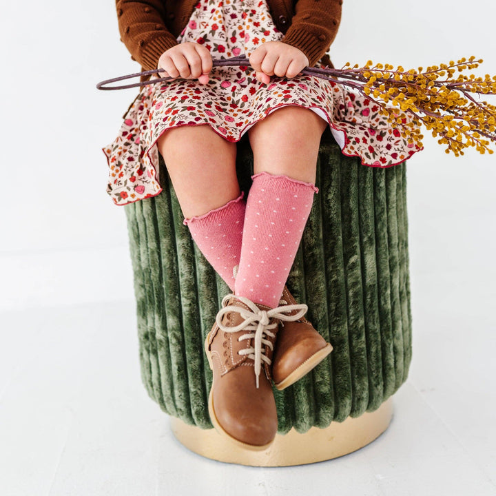 Toddler perched on a pumpkin wearing Little Stocking Co. Dottie Knee Socks in Old Rose, baby girl knee socks