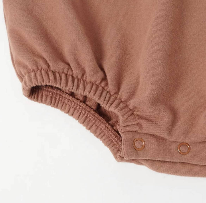 close up of one leg of the rusty red boho + bebe bubble rmper, showing quick change snap bottom and comfortable elastic leg