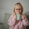 Child using cambridge blue training cup with straw.