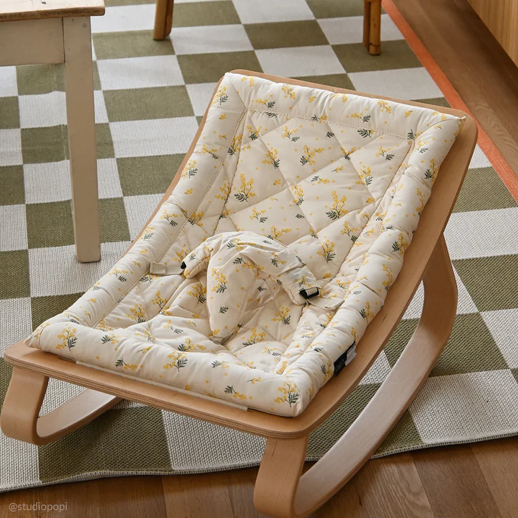 Angled studio view of the Charlie Crane Beech Wood Levo Rocker in milk fur, a baby rocker with natural rocking motion and French design