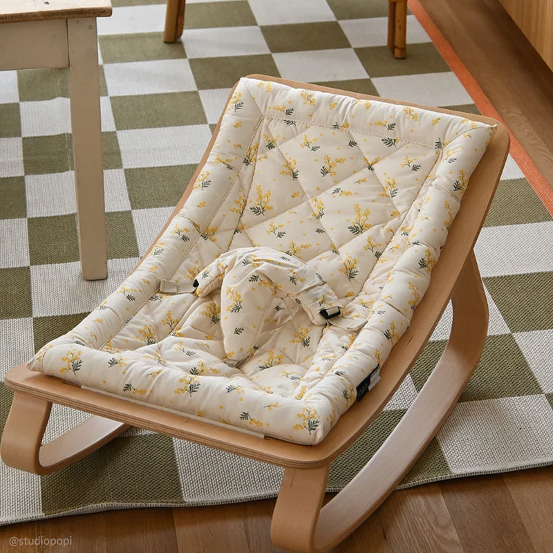 Angled studio view of the Charlie Crane Beech Wood Levo Rocker in milk fur, a baby rocker with natural rocking motion and French design