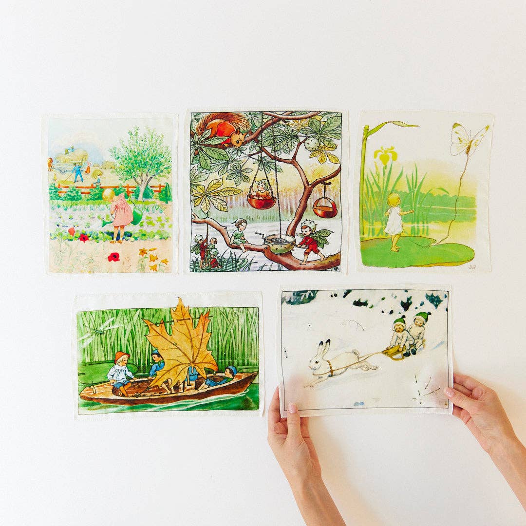 A hand holds up one printed silk from the Sarah's Silks Elsa Beskow Mini Mystery Playsilk collection