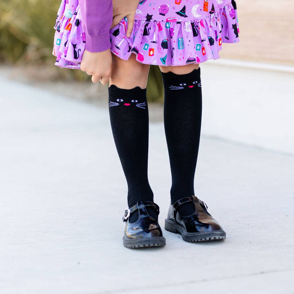 Little Stocking Co. Black Cat Knee High Socks paired with a floral dress, cute cat baby girl socks
