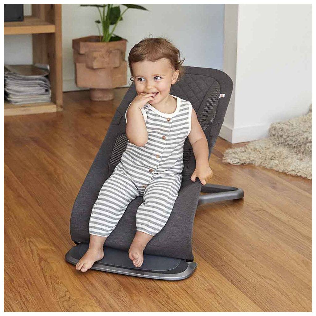 Toddler sitting in the charcoal Ergo baby bouncer