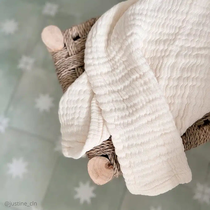 Minimal nursery styling highlights the Charlie Crane Doli Milk Blanket in milk as a practical swaddling blanket