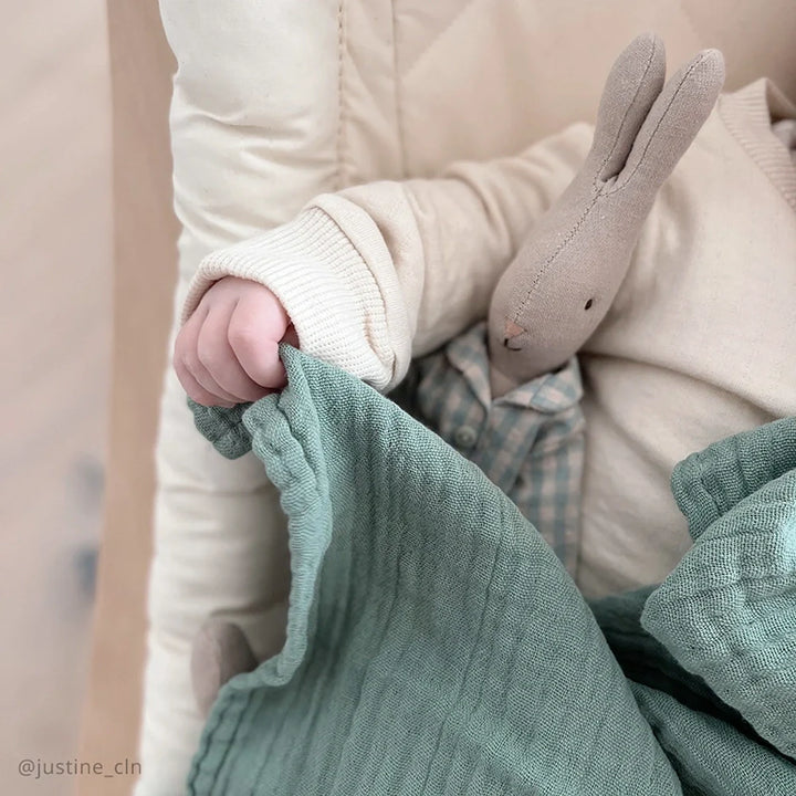 Modern baby essential shows the Charlie Crane DOLI Swaddle Set in milk camel and lichen crafted for infant use