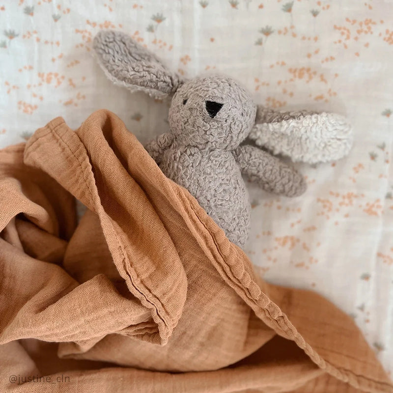 Calm nursery styling frames the Charlie Crane DOLI Swaddle Set in milk camel and lichen as a versatile receiving blanket