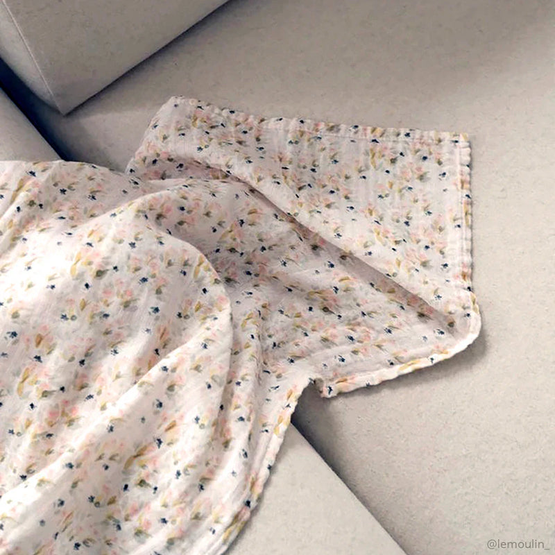 Minimal lifestyle image features the Charlie Crane DOLI Swaddle Set in milk camel and lichen designed as a baby swaddle
