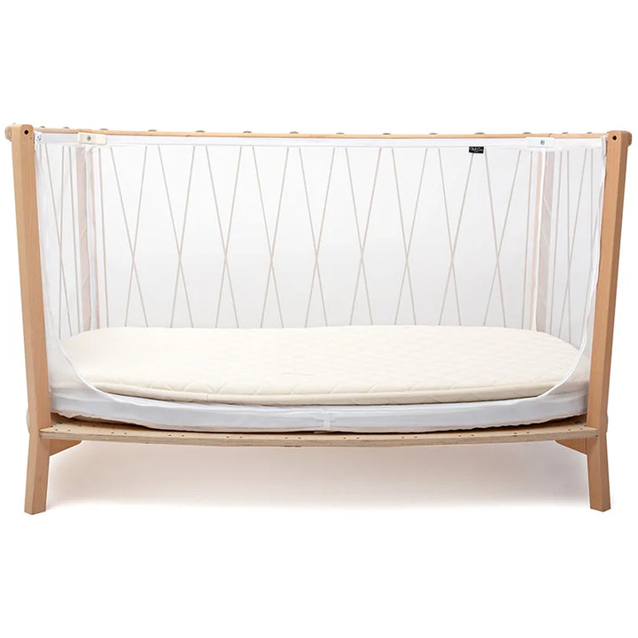 Cozy nursery corner displays the Charlie Crane KIMI Evolving Baby Bed in hazelnut with a safe coconut fiber mattress
