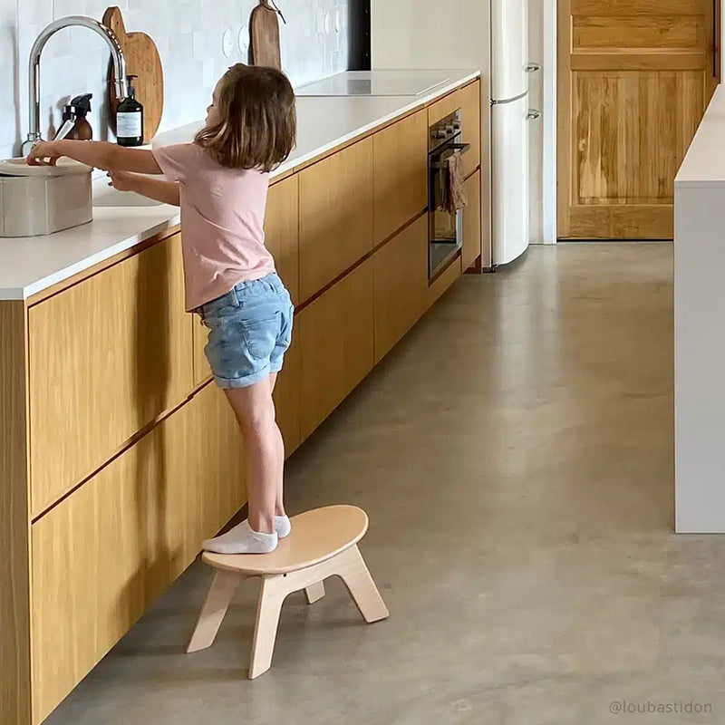 Cozy corner styling displays the Charlie Crane HIBO Wooden Stool in natural designed as an infant safe seat