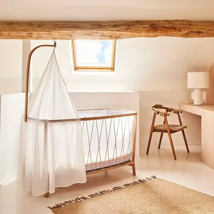 Softly styled room shows the KANO Bed Arrow Charlie Crane in natural as a French-inspired nursery accent