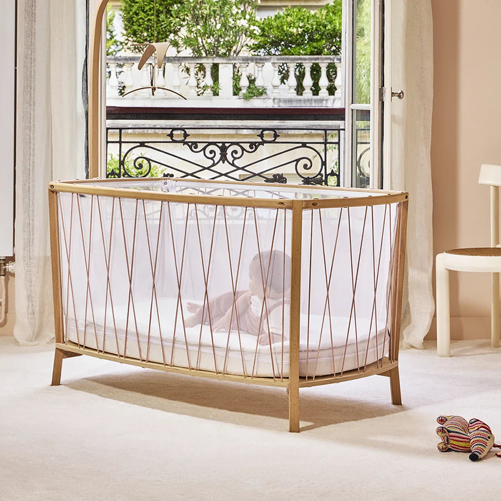 Floor-level perspective shows the Charlie Crane KIMI Evolving Bed in bois de rose as a toddler bed with durable wooden construction