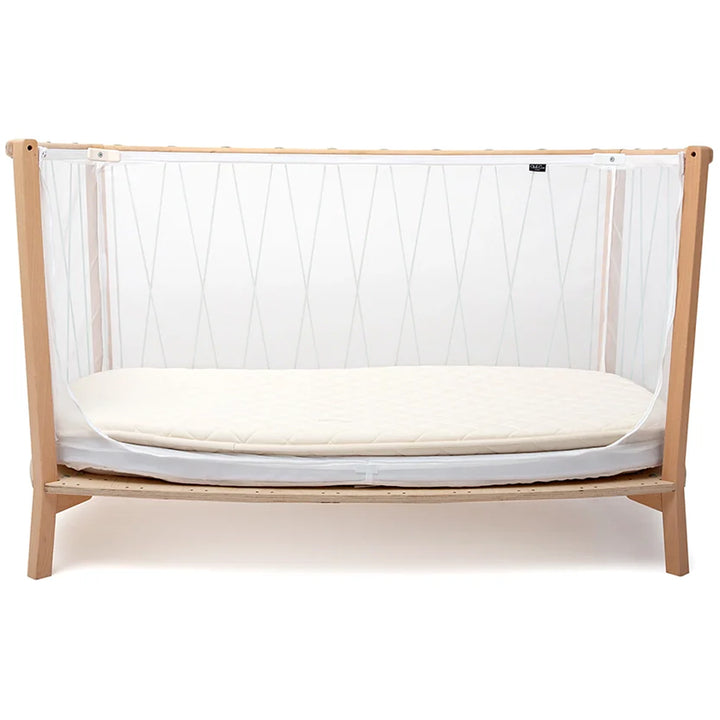 Neutral nursery decor displays the KIMI Evolving Baby Bed by Charlie Crane in hazelnut designed as a crib daybed