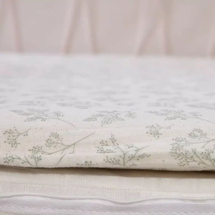 Pearl blossom nursery accent shows the KIMI Evolving Baby Bed Charlie Crane with natural organic crib sheet