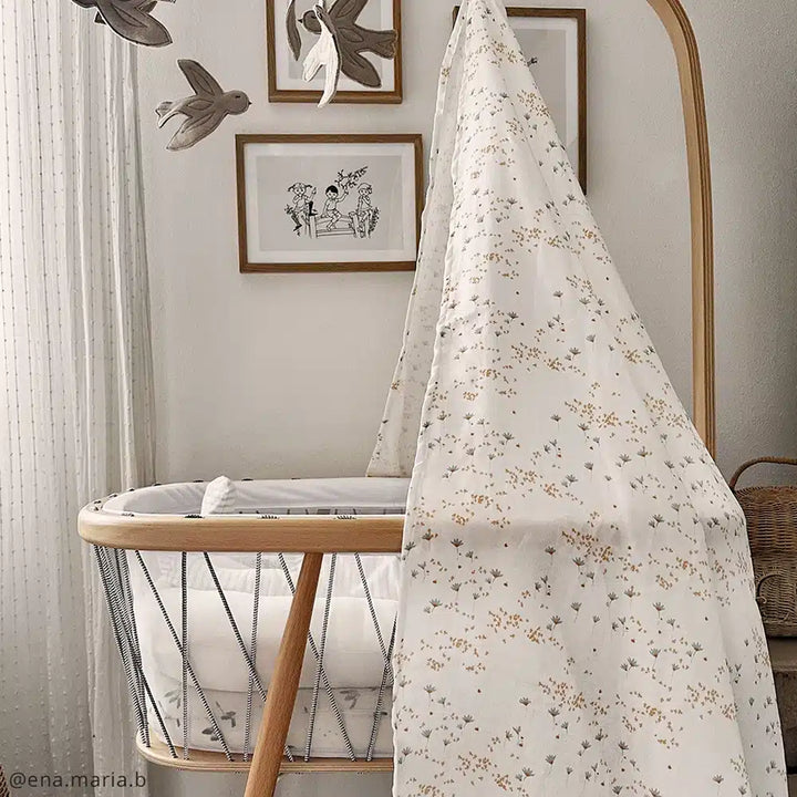 Soft nursery lighting highlights the Charlie Crane KUMI Canopy in pia designed to keep crib dark