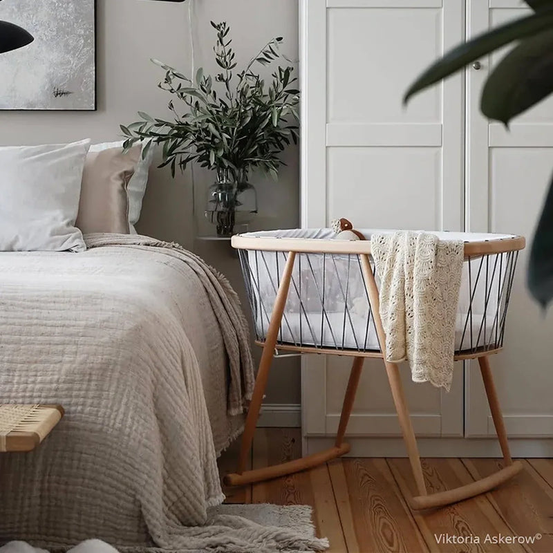 Warm interior scene features the Charlie Crane Cradle KUMI in hazelnut with infant safe construction