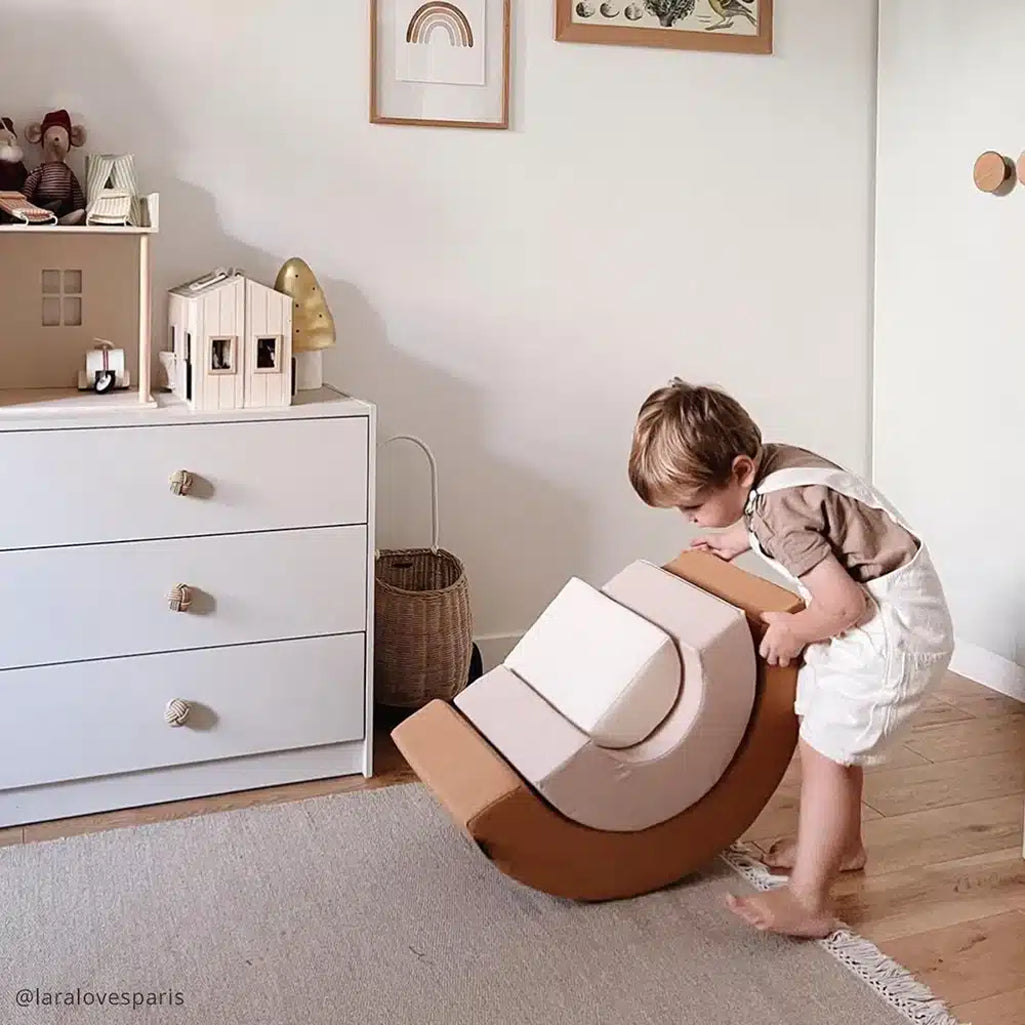 Modern nursery accent shows the Charlie Crane MILO Rainbow Toy in camel designed for baby play
