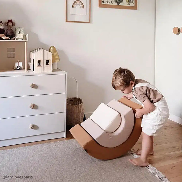 Modern nursery accent shows the Charlie Crane MILO Rainbow Toy in camel designed for baby play