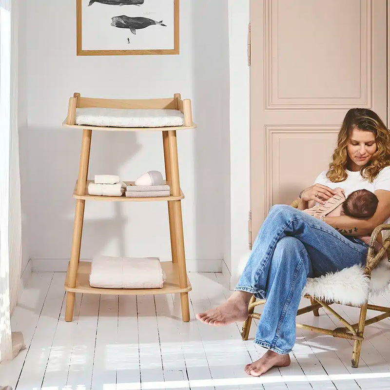 mother rocking baby to sleep next to charlie crane pago matress and changing table perfect for minimalist nursery 