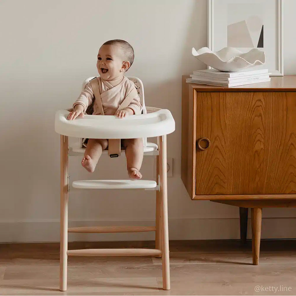 baby laughing in charlie crane high chair and holding detachable tobo highchair tray in midcentury inspired living room