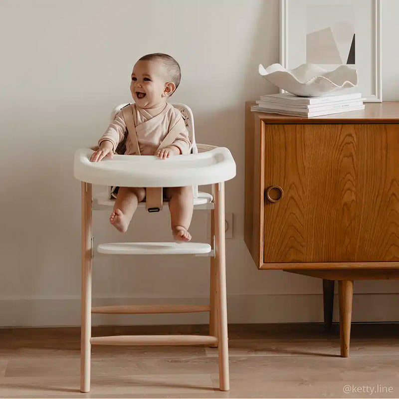 baby laughing in charlie crane high chair and holding detachable tobo highchair tray in midcentury inspired living room