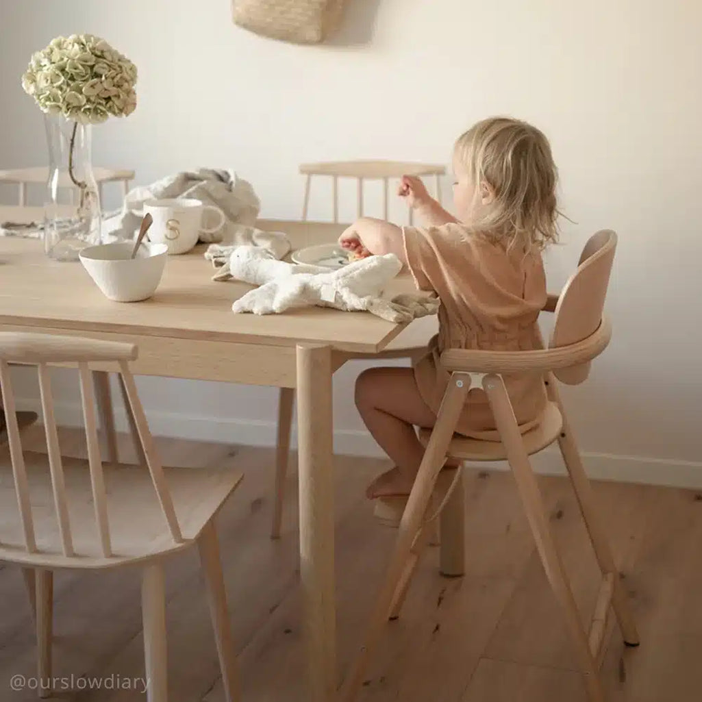 child sitting on charlie crane tobo high chair at sleek wooden dining table 