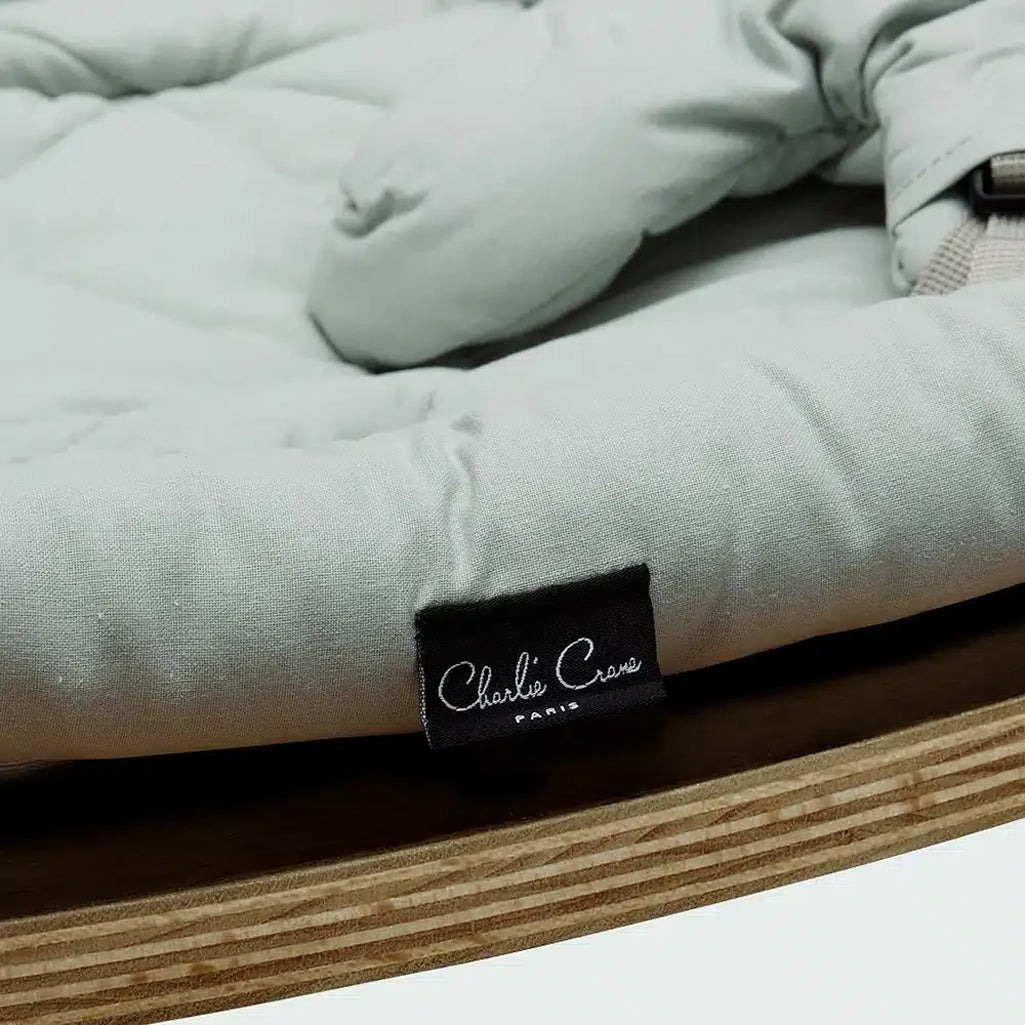 Angled studio view of the Charlie Crane Walnut Wood Levo Rocker in milk fur, a baby rocker with natural rocking motion