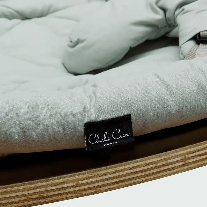 Angled studio view of the Charlie Crane Walnut Wood Levo Rocker in milk fur, a baby rocker with natural rocking motion