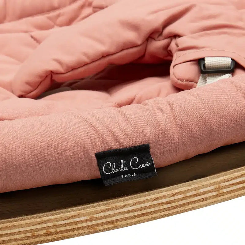 Gentle angles reveal the Charlie Crane Walnut Wood Levo Rocker in organic milk, built for sustainable baby comfort