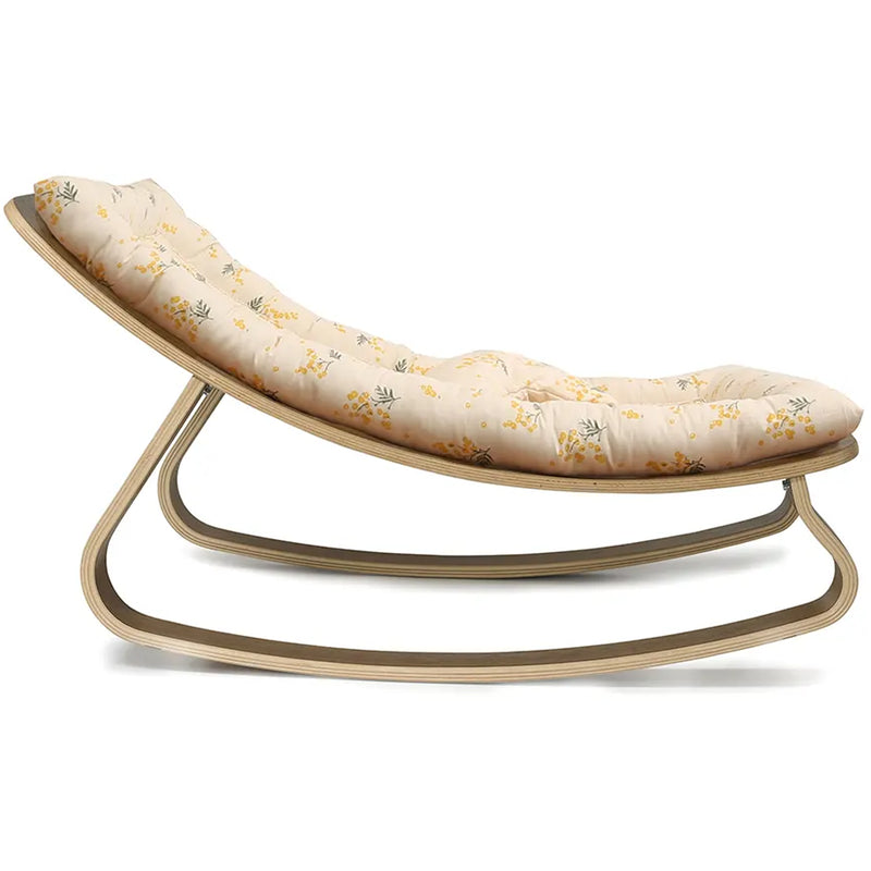 Side profile of the Charlie Crane Walnut Wood Levo Rocker in organic milk, designed with a rounded shape for infant comfort