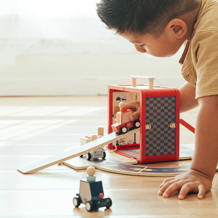 Child playing with the Wonder & Wise Take with Me Garage wooden toy on floor