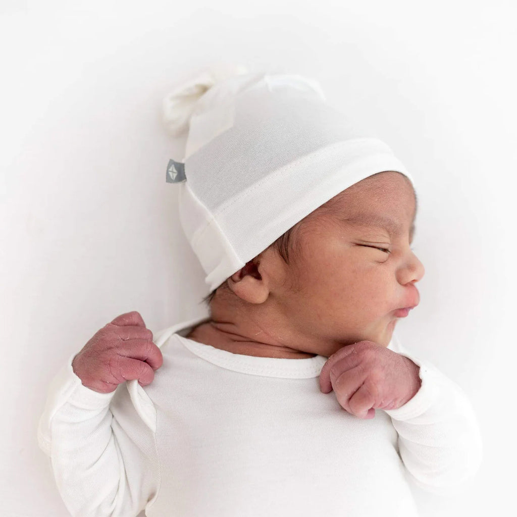 young baby wearing KyteBaby white baby hat