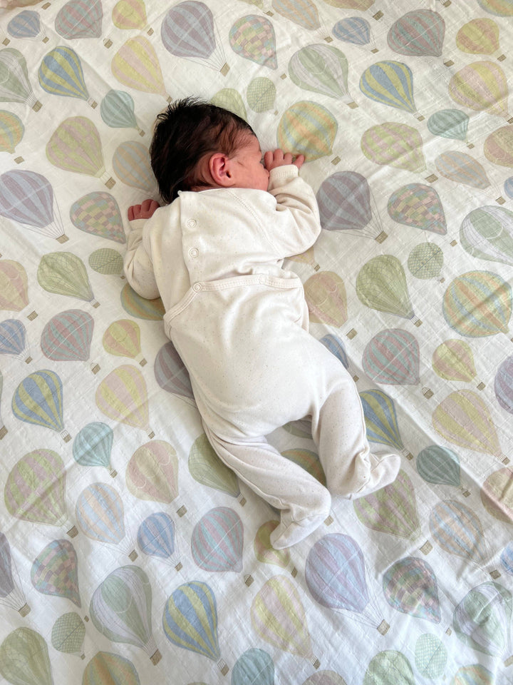 Newborn resting on Little Threads pastel air balloon muslin blanket, soft swaddle blanket for comfort, warmth, and supervised lounging