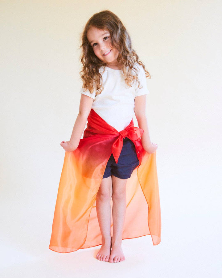 Child wearing a colorful cape Sarah’s Silks desert playsilk