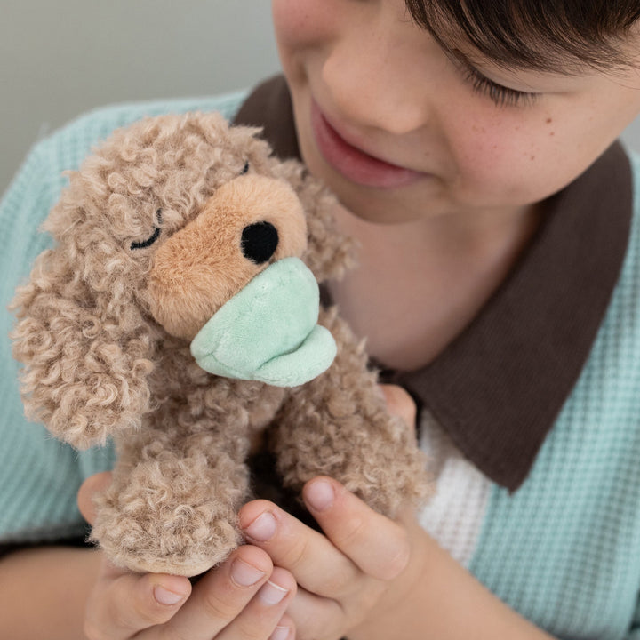 Child cuddling the Dinkum Dolls Binky Puppy Benny gold plush dog toy