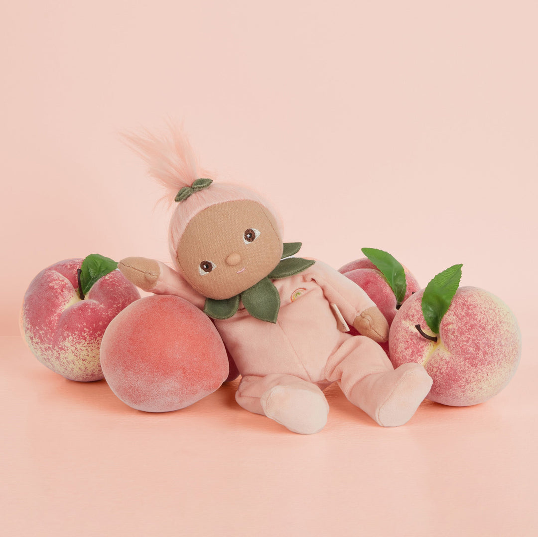 Dinky Dinkums Peggy Peach soft doll reclining among fresh peaches, Dinkum Dolls