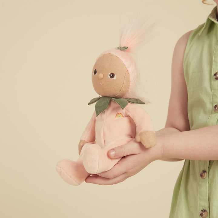 Child's hands holding the Peggy Peach Dinky Dinkums weighted plush doll from Dinkum Dolls