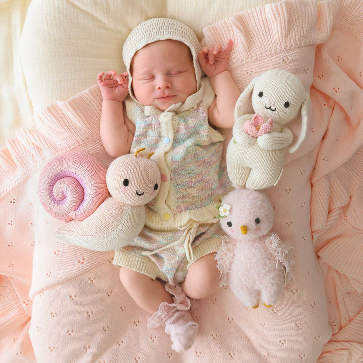 Cuddle + Kind Baby Snail soft pink peony — sustainably made hand-knit stuffed animal for nursery