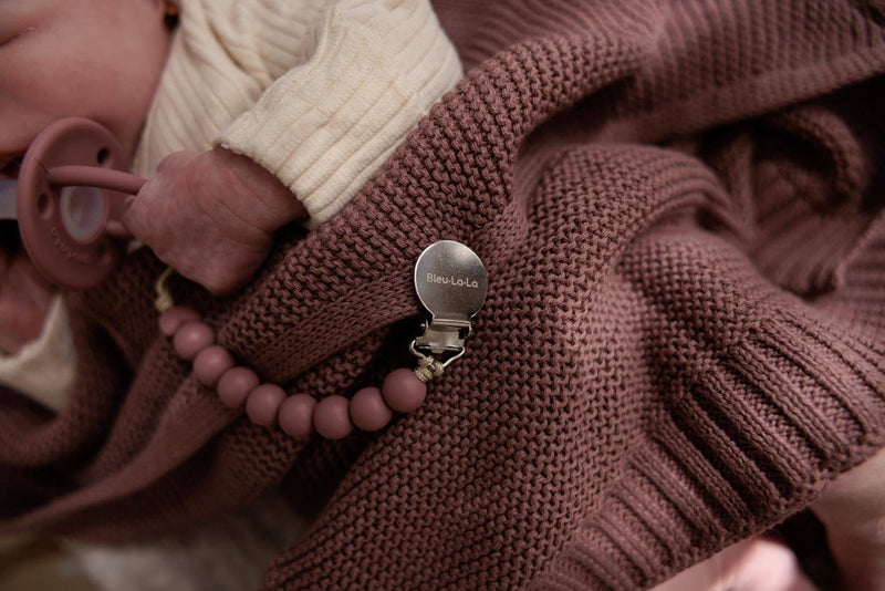Closeup of the Heritage Knit 100% Organic Cotton Swaddle Baby Blanket in Sugar plum, with Bleu La La Pacifier