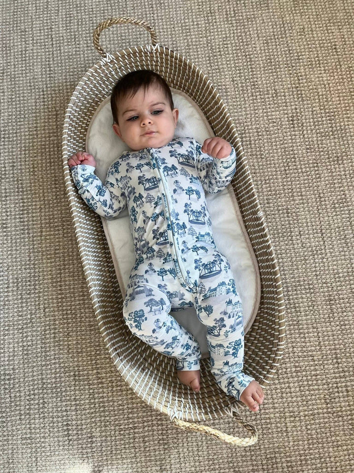 Bamboo footie in blue toile print from Little Threads on baby resting in a bassinet