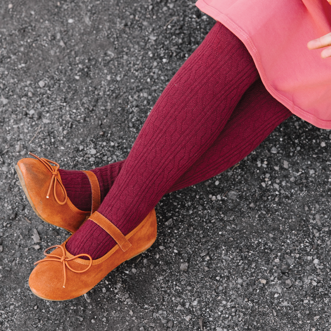 Baby girl wearing Little Stocking Co. Burgundy Cable Knit Tights with mary jane shoes and a pink dress