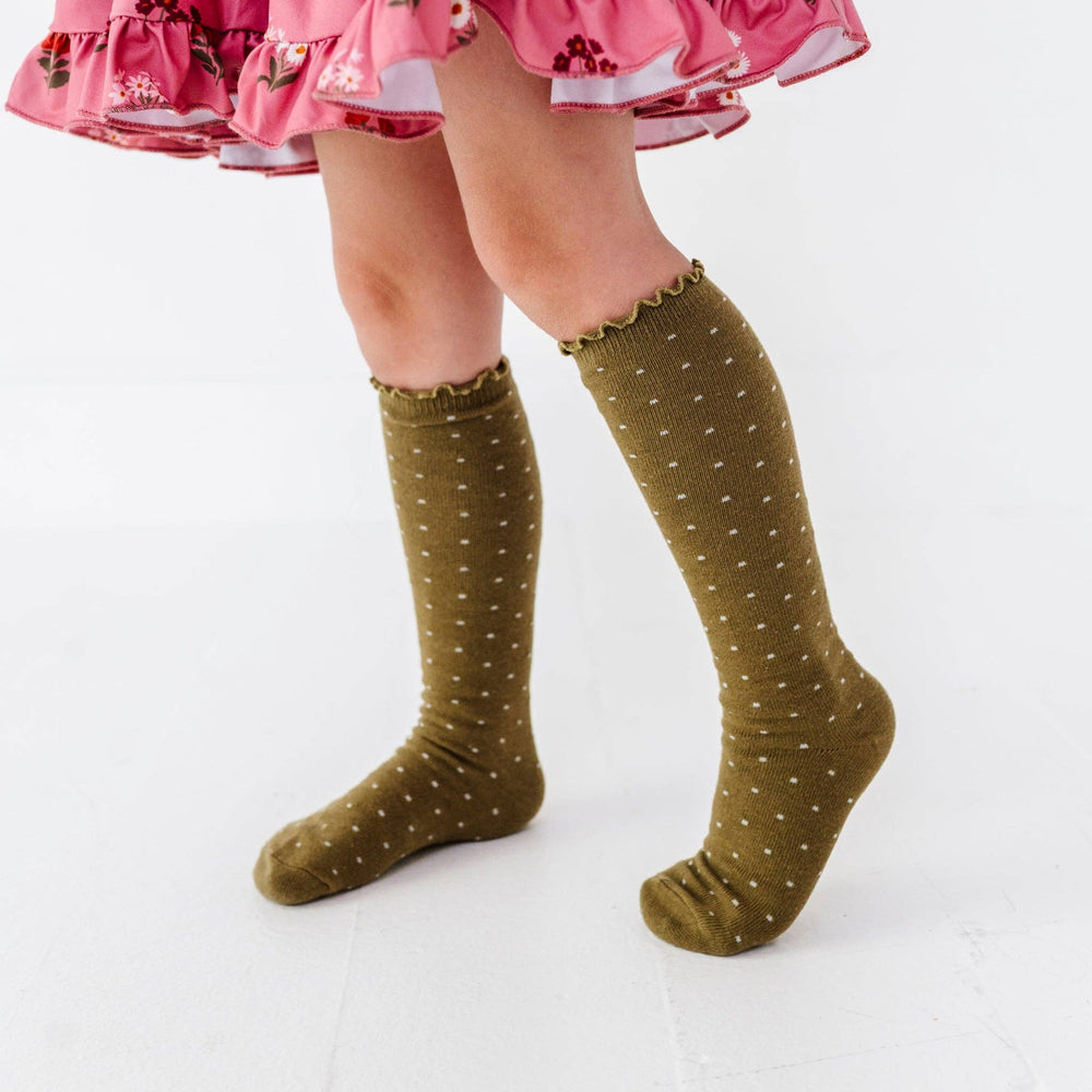 Girl wearing Little Stocking Co. Dottie Knee Socks in Olive with a pink tutu skirt, polka dot knee socks