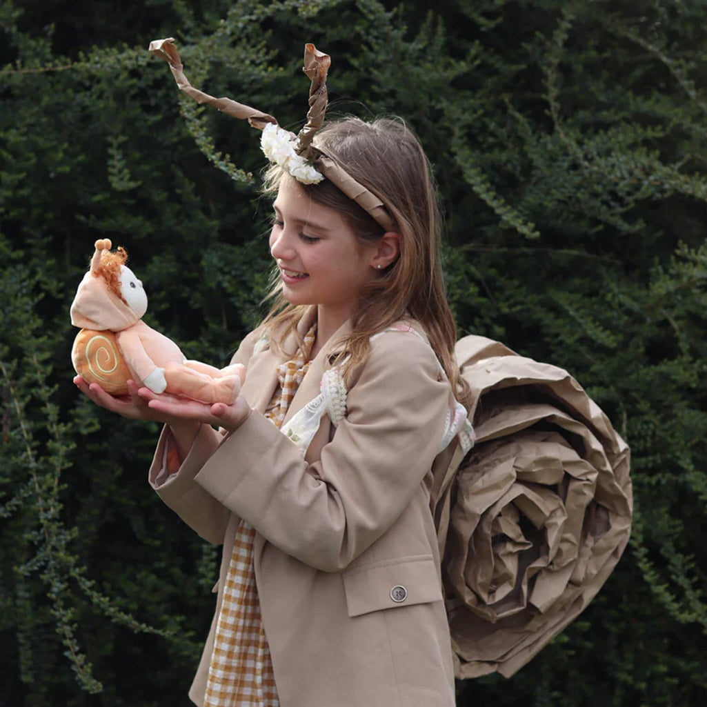 child gently holding olliella pale red headed doll in snail outfit as they smile at each other 